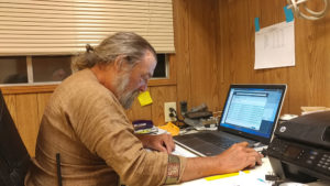 Viscount Edward working on a laptop in an office at Pennsic